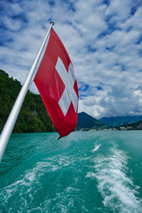 Red flag on sea against sky