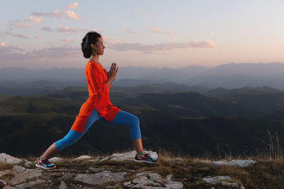 Young girl is doing yoga and fitness outdoors in a beautiful mountain landscape. sunset light