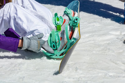Low section of man wearing snowboard sitting on snow