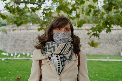 Portrait of young woman standing against tree