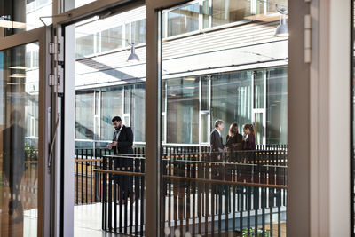 Businessman using mobile phone while colleagues discussing in background