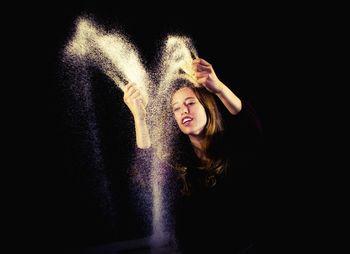 Portrait of young woman against black background