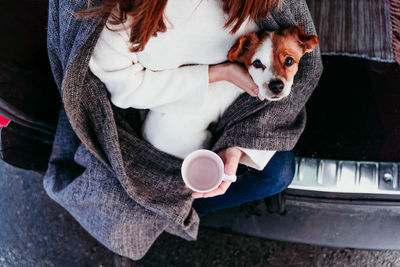 Midsection of woman with dog and coffee
