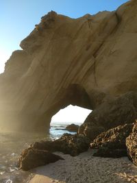 Rock formation on beach against sky