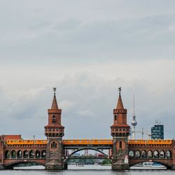 Low angle view of bridge over river against cloudy sky