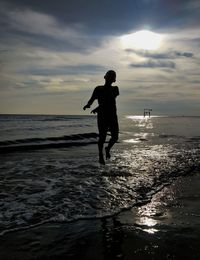 Silhouette man on beach against sky during sunset