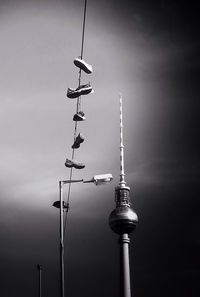 Low angle view of communications tower against cloudy sky