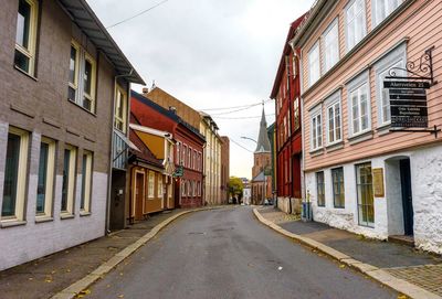 Empty road amidst buildings against sky