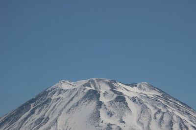 Low angle view of snowcapped mountain against clear blue sky