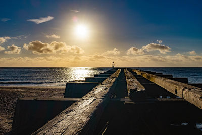 Pier over sea against sky during sunset