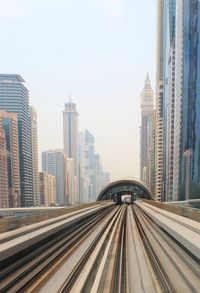 Railroad tracks amidst building in city against sky