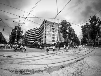 Cars on city street by buildings against sky