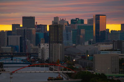 Modern buildings in city against sky during sunset