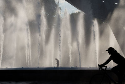 Silhouette man riding bicycle against sky