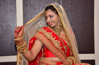 Smiling beautiful woman in wedding dress standing against wall