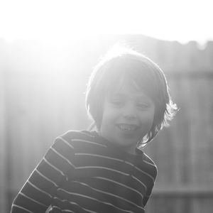 Smiling boy looking away against fence