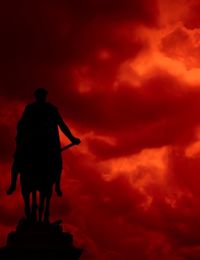 Silhouette of statue against dramatic sky