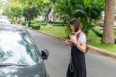 Side view of woman with umbrella on road