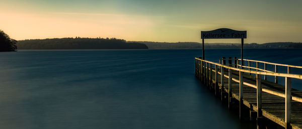 Pier over lake against sky during sunset