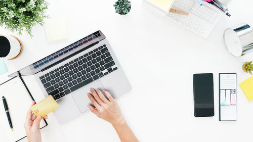 Cropped hand of woman shopping online through laptop