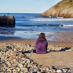 Rear view of woman sitting on beach