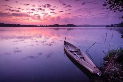 Boat moored in lake with clouds reflection