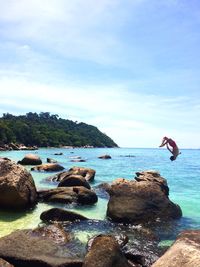 Man jumping in sea against sky