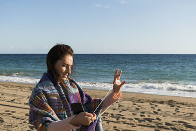 Woman unraveling her headphones on the beach