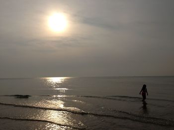 Silhouette man on beach against sky during sunset