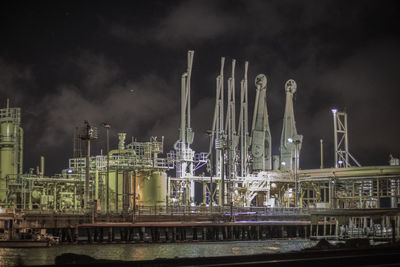 Illuminated factory against sky at night