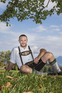 Portrait of man in traditional clothing sitting against sky