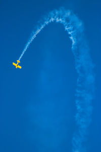 Low angle view of airplane flying against clear blue sky