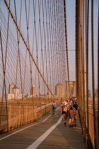 People on brooklyn bridge against sky