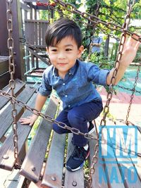 Boy looking away while playing on jungle gym at playground