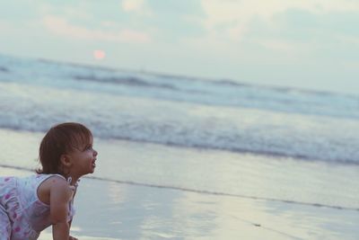 Side view of baby girl at beach during sunset