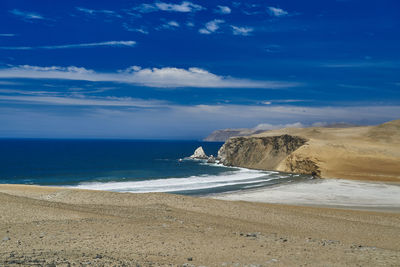 Desolate and vast landscape of paracas at the coastline of peru. blue sky clouds, sandy desert beach