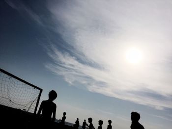 Silhouette people playing soccer against sky during sunset