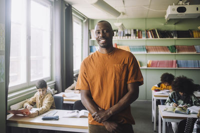 Portrait of confident male teacher with students in classroom