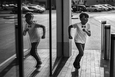 Rear view of boy running near glass wall