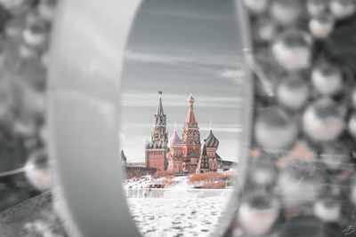 View of snow covered palace against sky seen through window