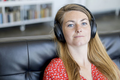 Portrait of young woman listening music at home