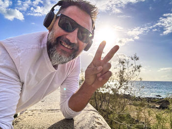 Portrait of man wearing sunglasses against sea against sky