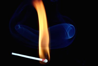 Close-up of burning match against black background
