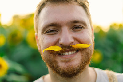 Man with yellow flowers in mustache. breathe free. a man has fun in nature.