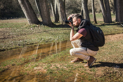 Full length of man photographing in forest