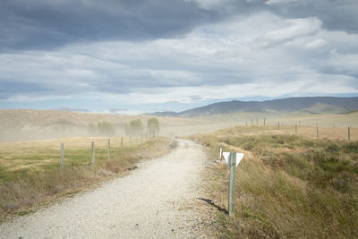 Road amidst field against sky