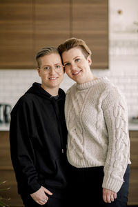 Portrait of smiling young lesbian couple standing together at home