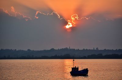 Silhouette sailboat in sea against sky during sunset