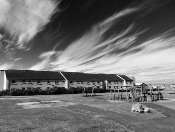 Houses on road against cloudy sky