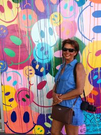 Portrait of smiling young man standing against graffiti wall